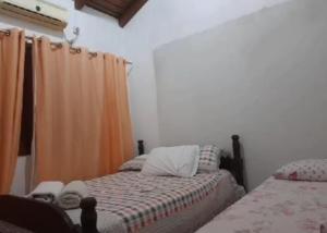 圣加布里埃尔Pousada Claudia e Juliano的一间卧室配有两张床和橙色窗帘