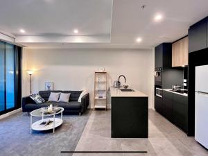 堪培拉Brand New Stylish 1BR Apartment, Specious Space, Free Parking, Self Check-in的厨房以及带沙发和桌子的客厅。