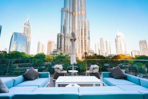 迪拜THE CLOSEST building to Burj Khalifa with Fountain View in Address Opera Residence的一个带蓝色沙发的屋顶露台和城市天际线