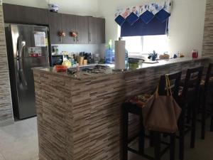 巴拿马城MM VILLA的厨房配有带椅子的柜台和冰箱。