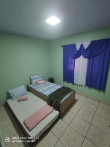 马卡埃Casa Muro Alto-Sana Rj的一间卧室配有一张床和一个带紫色窗帘的窗户