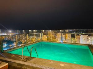 利马Barranco Aparment Luxury的一座游泳池,在晚上在一座建筑的顶部