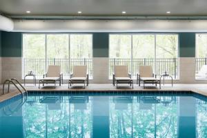 雷丁雷丁华美达有限酒店的一座游泳池,里面设有桌椅和窗户