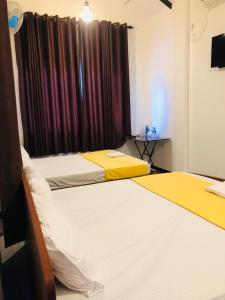 IbbagomuwaLotus cool hotel and restaurant的一间卧室设有两张床,窗户配有窗帘