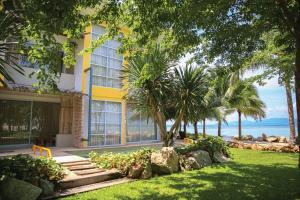 班泰Summer Luxury Beach Resort & Spa的一座黄色的建筑,有树木和海洋背景
