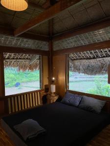 Làng CacTớ Dày Du Già Village的卧室配有床,位于带2个窗户的房间