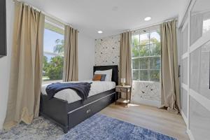 西棕榈滩Palm Wave Says - 5 min to Best Locations的一间卧室设有一张床和一个大窗户