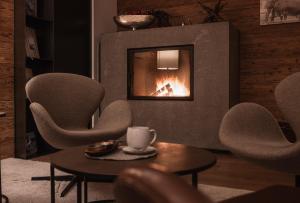 菲根贝格ASTER Boutique Hotel & Chalets的客厅配有椅子和壁炉