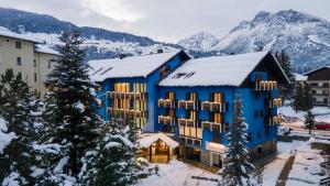 博尔米奥白塔克里门迪酒店的一座蓝色的建筑,背景是白雪 ⁇ 的山脉