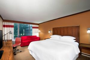 堪萨斯城堪萨斯城机场福朋喜来登酒店的酒店客房,配有一张床和一张红色椅子