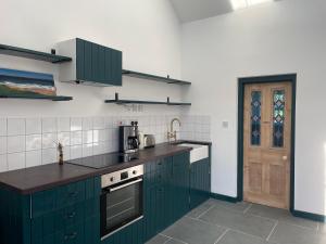 法尔茅斯Tresahor Studio的一间设有绿色橱柜和门的厨房