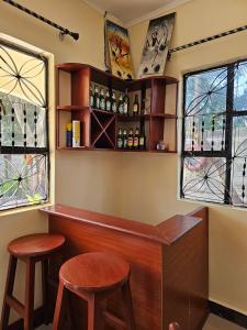 Boma la NgombeB-MORE COMFORT STAY的带2张凳子的酒吧,位于带窗户的房间里