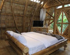 外南梦The Osing Bamboo Resort - a LIBERTA Collection的一间设有床铺的卧室,位于带窗户的房间内