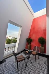 Bạc LiêuThiên Ân Boutique Hotel的阳台配有桌椅和红色墙壁。