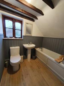 KnaptonGardeners Cottage near the Norfolk Coast的浴室配有卫生间、盥洗盆和浴缸。