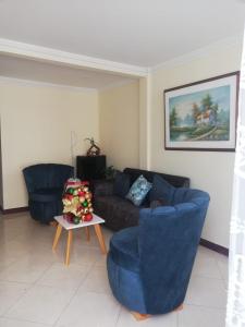 菲兰迪亚Casa de Ensueño en Filandia: Tu Hogar Lejos de Casa的客厅配有2把蓝色椅子和1张沙发