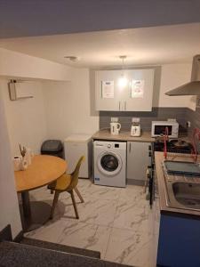 奥尔德姆1 Bedroom Flat Available的厨房配有桌子、炉灶和洗衣机。