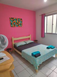 皮乌马Aquarela Suítes的一间卧室配有一张床和粉红色的墙壁