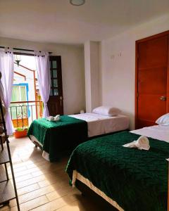 菲兰迪亚Hotel Casa Helena的一间卧室设有两张带绿床单的床和窗户。