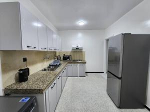 拉巴特Residence Al Kasbah - VacayX - Chic Triplex 3BR -RABAT的厨房配有白色橱柜和不锈钢冰箱