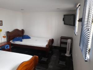 蒙特内哥罗HOTEL PARAISO DE LAS GEMELAS的客房设有两张床和一台墙上的电视。