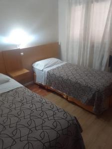 马德普拉塔Hotel Alma di Mare的配有衬衫的酒店客房内的两张床