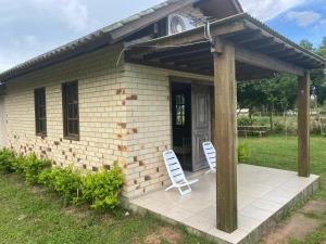 托雷斯Cabana de Campo, Praia e Piscina em Torres, Não fornecemos lençóis, No proporcionamos sábanas的两把白色椅子坐在大楼前的庭院