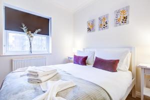 罗姆福特Beautiful Two Bedroom Apartment with Free Parking!的卧室配有一张带紫色枕头的大型白色床。