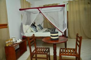 Stone TownLa Neisha Hotel Zanzibar的配有床和两把椅子及一张桌子的房间