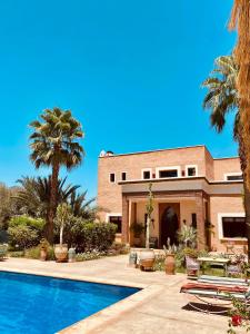 马拉喀什La Villa Des Golfs & PinkCactus的一座带游泳池和棕榈树的房子