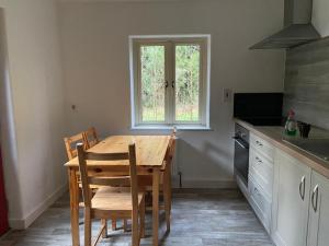 博伊尔Carrickamore Cottage的厨房配有木桌、椅子和窗户。