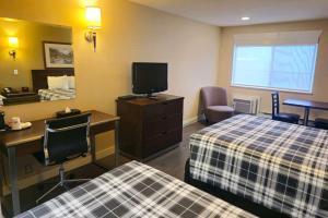 坎卢普斯Rodeway Inn & Suites的酒店客房设有两张床、一张桌子和一台电视。