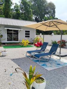Casa LiLa Tiny Stay & Pool Kota Bharu,free wifi,free parking的房屋前的一把椅子和一把伞