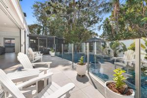 黄金海岸5BR Mermaid Waters Luxury Home的一个带白色椅子的庭院和一个游泳池