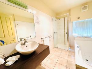 巴拉腊特城市美景康福特茵酒店及套房的浴室配有水槽、淋浴和浴缸。