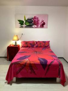 TaputapuapeaBungalow climatisé chez Kim的一间卧室配有红色的床和粉色毯子