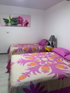 TaputapuapeaBungalow climatisé chez Kim的一间卧室配有两张带紫色和橙色床单的床