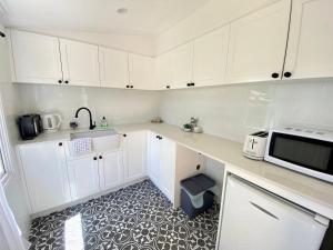 斯普林伍德Mapleton Park Cottage的厨房配有白色橱柜和微波炉