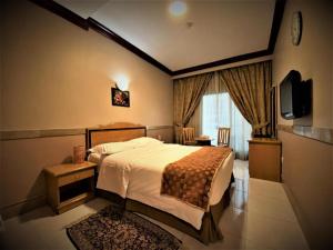 迪拜San Marino Hotel的一间酒店客房,配有一张床和一台电视