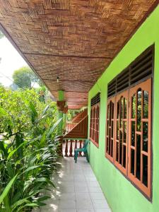 武吉拉旺Wisma Batu Mandi and offers jungle tours的绿色建筑的门廊,设有木制天花板