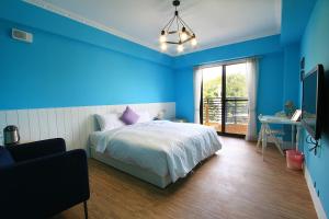 垦丁大街优闲民宿的一间蓝色卧室,配有一张床、一张书桌和一台电视