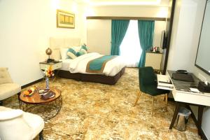 木尔坦Faletti's Grand Hotel Multan的酒店客房配有一张床、一张沙发和一张书桌。