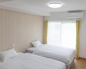 宫古岛BiBi Hotel 宮古空港前的酒店客房设有两张床和窗户。