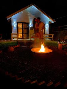 大普拉亚Tiny House Canjerana- Morro do Eurico - Praia Grande-SC的一对夫妇在房子前面的火边跳舞