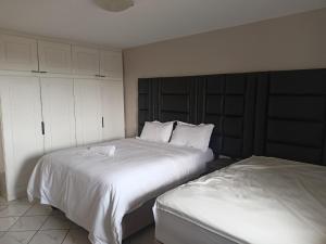 埃祖尔韦尼Early Riser的一间卧室配有两张带白色床单的床