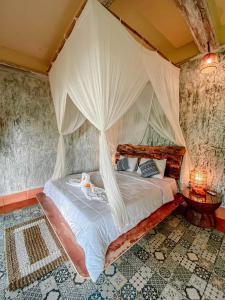 TampaksiringBali Inang Jungle View的一间卧室配有带窗帘的天蓬床
