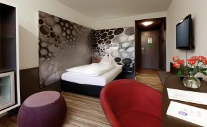 韦因费尔登Hotel Thurgauerhof Self-Check-in的酒店客房,配有一张床和一张红色椅子