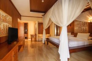 乌布Champlung Sari Villa & Spa Ubud的一间卧室配有一张天蓬床和一台电视机