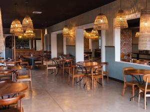 KhorixasLodge Damaraland的餐厅设有木桌、椅子和吊灯。