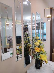 海阳Bach Dang Apartment Hai Duong的花瓶里花的墙上的一组镜子